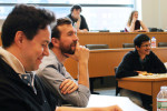 A small group of people sitting in a classroom or lecture hall, engaged and smiling during a discussion or presentation.